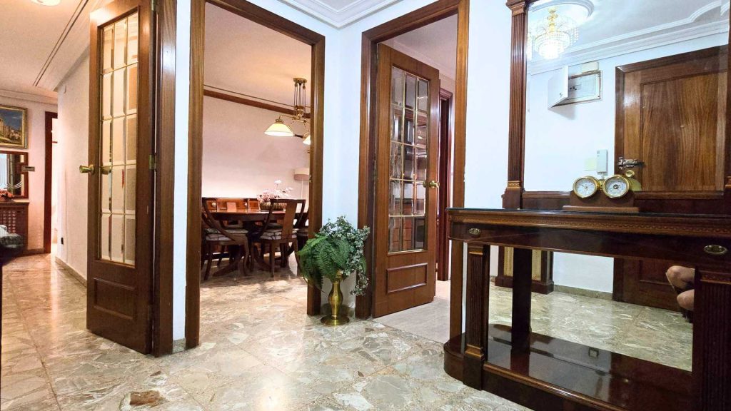 hall de la casa, con un mueble antiguo y varias puertas